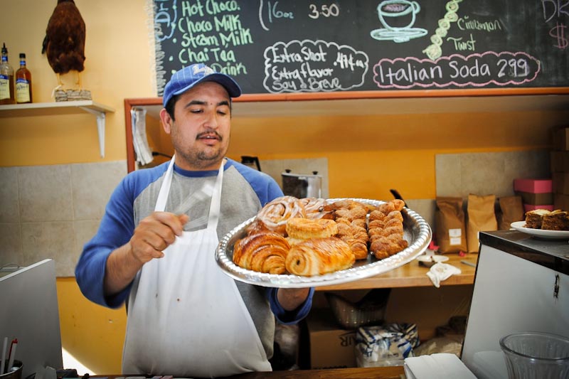 Angel Rocha shows off a diverse sampling of baked goods prepared at Golden Wheat, in the Central District. (Photo by Anna Goren)