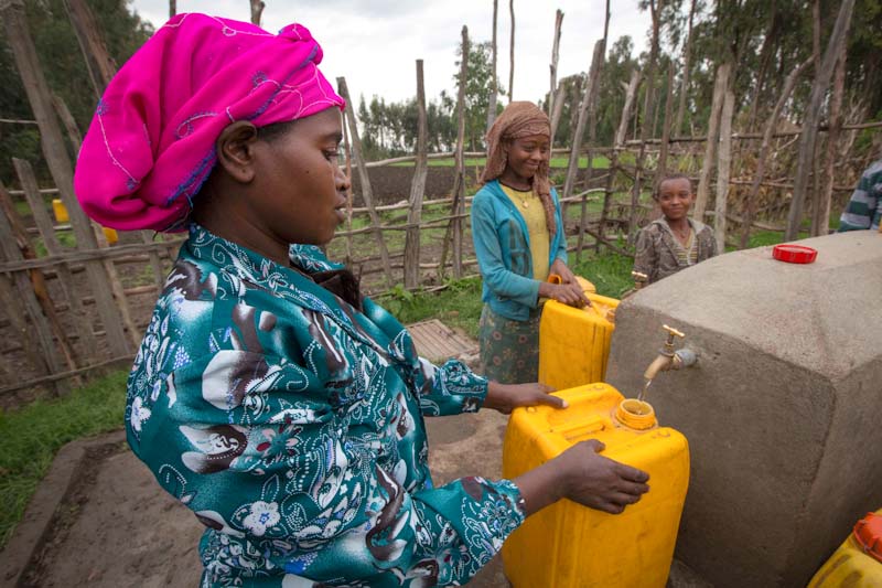 Ethiopian women fill up jugs at a water point constructed by a Seattle-based NGO. (Photo courtesy Water 1st International)