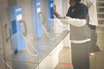 A detainee at the Northwest Detention Center makes a phone call. Stays in the facility range from just a few hours to several years in rare cases. (Photo by Alex Stonehill)