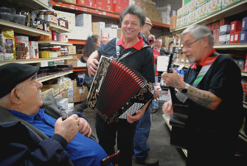 Lennu Luzzi and his band serenade John Croce (left) with familiar Italian songs during his 90th birthday celebration in the store. (Photo by Anna Goren)