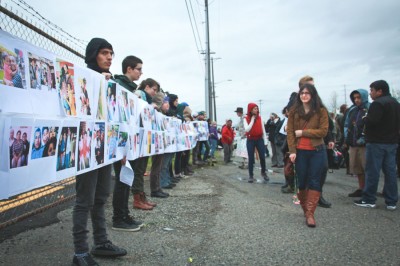 Protestors hold up wall of photos of those locked up & deported