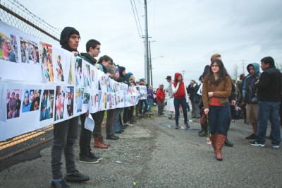 Protestors hold up wall of photos of those locked up & deported. (Photo by Lael Henterly)