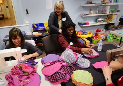 Mary Jacobson smiles as Carol Hendricks gives Funmi Ajasin a quick massage as they work on the Days for Girls hygiene kits at the Church on the Ridge in Snoqualmie. (Photo by Lindsey Wasson / The Seattle Times)
