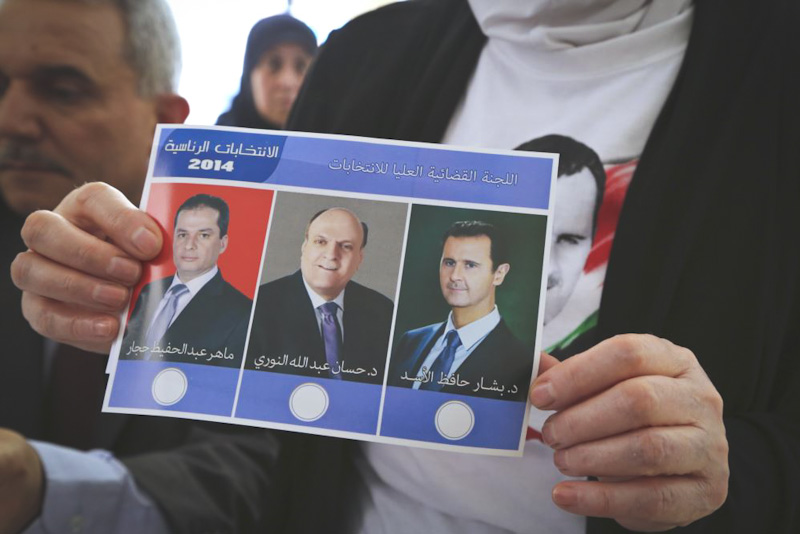 A Syrian refugee in Beirut holds a ballot from Tuesday's multiparty presidential elections. Bashar Al-Assad (right) is almost assured victory. (Photo from Reuters)