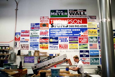 The wall of old signs inside of Thompson Signs' warehouse serves as a visual reminder of the mostly white, male political candidates in the northwest. (Photo by Lucas Anderson / UW Election Eye)