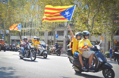 A motorcade of scooters and motorcycles flying Catalonian flags passes through the streets of Barcelona. With a strong economy and a unique language and culture, many Catalonians want to see their region seceed from the rest of Spain. (Photo by Seth Halleran)