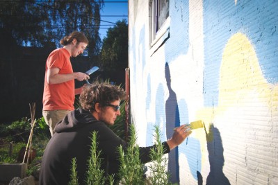During his visit to Seattle, South African comics artist Jean de Wet (front, with local collaborator James Stanton) is painting a mural on the Cappy's Boxing Gym building in the Central District. (Photo by Ana Sofia Knauf)