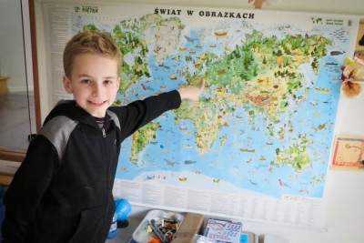 Fourth grader Arthur Gwozdz of Newcastle points at his parents’ native Poland on a map in his family’s living room. (Photo by Kyle Haddad-Fonda)
