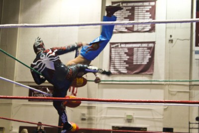 El Heroe delivers a kick as Ave Rex somersaults over him (Photo by Olivia Fuller).