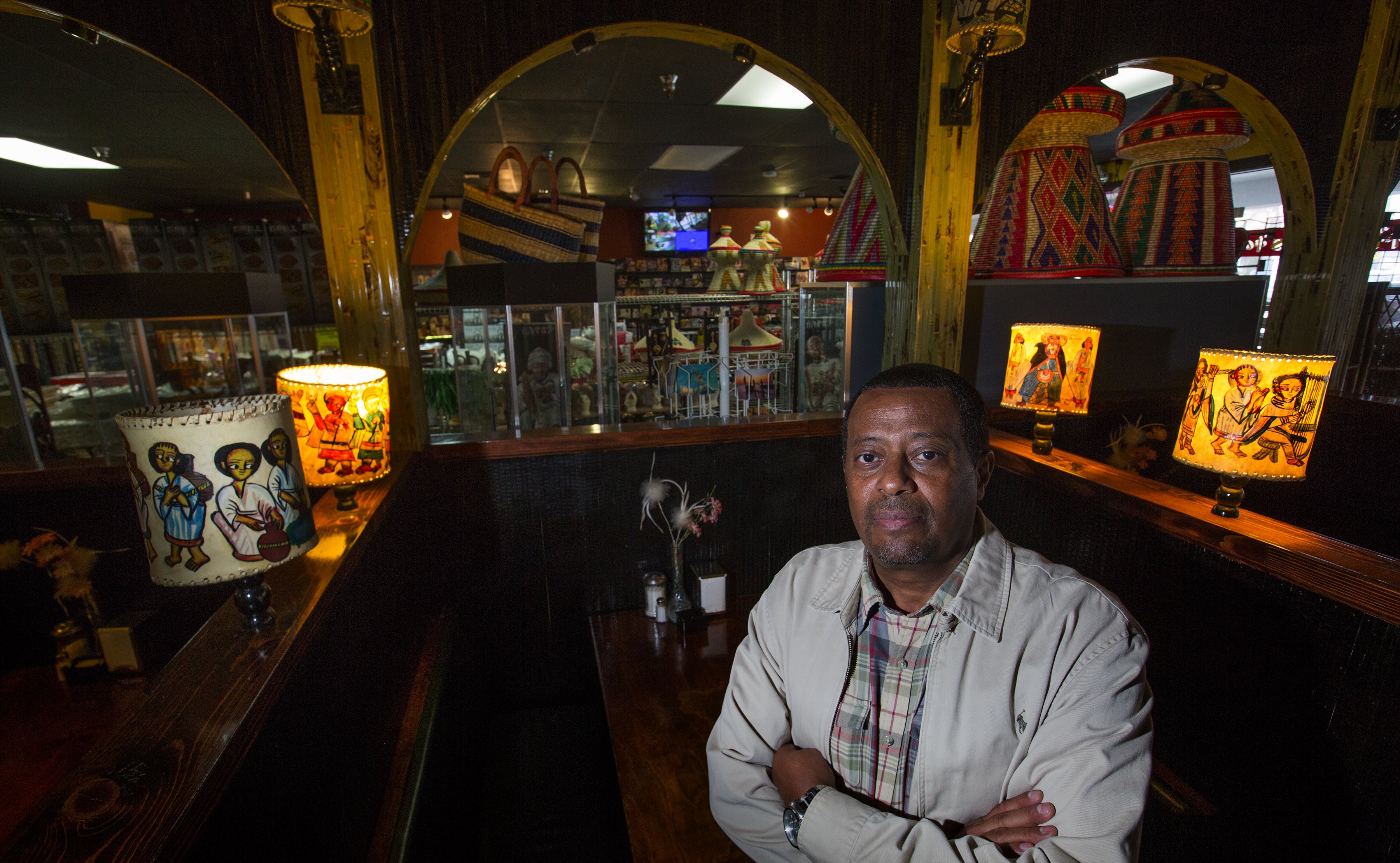 Berhane Amanuel, owner of East Africa Imports (and restaurant) stands inside his Seattle restaurant. His store can be seen through the arches at top. East Africa Imports is a tiny little story and eatery in The Promenade, a shopping center in the Central District. It was opened in 2002 by Amanuel and his Central District native wife and they put 100k+ into adding a restaurant about 5/6 yrs ago. They recently found out that Vulcan plans to demolish/develop the shopping center meaning they'll have to move and may not be able to afford to open a restaurant again.