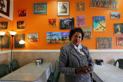 Jane Kagira owns the Kenyan restaurant Safari Njema in Columbia City, host of the first Migrating Meals conversation. The scenes on the wall mainly are depictions of Kenya. (Photo by Alan Berner / The Seattle Times)